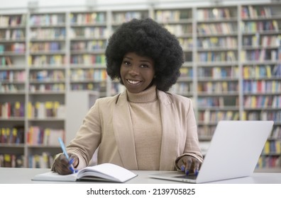 Smiling African University Student Using Laptop Computer Studying, Learning Language, Taking Notes, Online Education Concept. Portrait Of Successful Freelancer Working Sitting At Workplace  