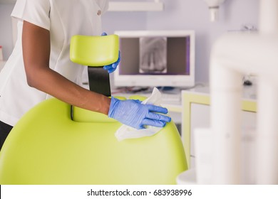 Smiling African Woman Dentist Cleaning Up Dentist Chair After Procedures