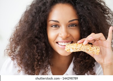 Smiling African Woman Eating A Heathy Cereal Snack Bar.