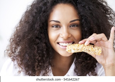 Smiling African Woman Eating A Heathy Cereal Snack Bar.