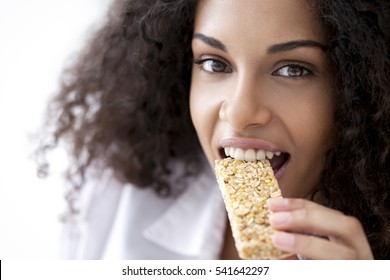 Smiling African Woman Eating A Heathy Cereal Snack Bar.