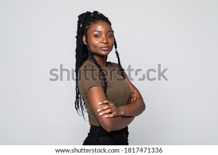 Smiling african woman standing with arms folded on gray background