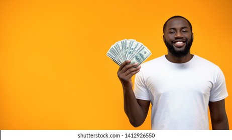 Smiling African-American man showing bunch of dollars, template for text, ad - Shutterstock ID 1412926550