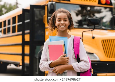 Smiling african-american schoolgirl going back to school with books and copybooks waiting for schoolbus. New academic year semester - Powered by Shutterstock