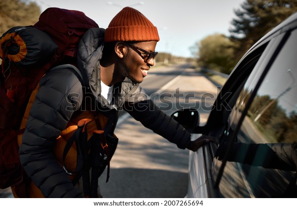 Smiling\
afro american guy stopped car to ask for further direction. Lost in\
forest, travelling alone. In mood for camping, new experience and\
adventure. Tourism and active leisure\
concept