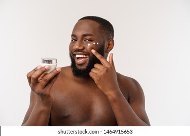 Smiling Afro Man Applying Cream On His Face. Man's Skin Care Concept