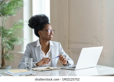 Smiling Afro Woman In Blazer Wear Glasses Working At Laptop Computer At Home Office, Dreaming About Weekend Vacation, Looking Away. Black Girl Student Takes A Break From Work. Positive Thinking