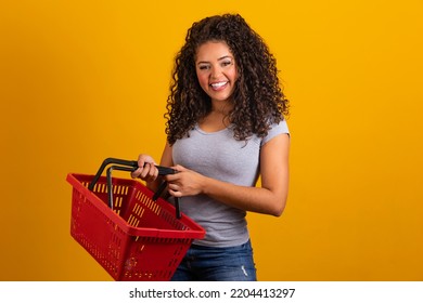 Smiling afro woman holding empty shopping basket looking at camera smiling