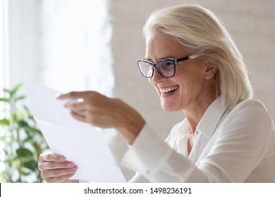 Smiling Aged Businesswoman Hold Paper Document Read Good News In Correspondence, Happy Senior Woman Worker Look Through Paperwork Feel Excited Overjoyed With Approval Letter Or Contract