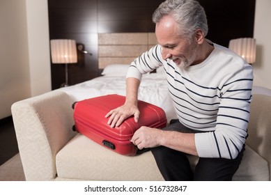 Smiling aged man preparing his luggage for a trip