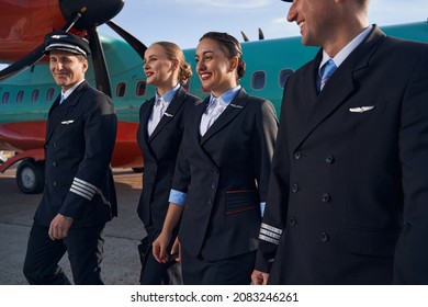 Smiling Airplane Crew Members Walking Together On Runway