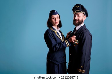 Smiling Airplane Pilot And Flight Attendant Couple In Uniform Looking At Camera, Studio Medium Shot Portrait. Airplane Crew, Plane Captain And Air Hostess Standing, Aircrew