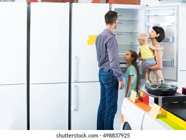 Smiling American  Family Of Four Shopping New Refrigerator In Home Appliance Store 
