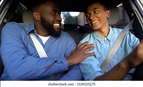 Smiling american father praising son learning to drive auto, parent help, family - Powered by Shutterstock