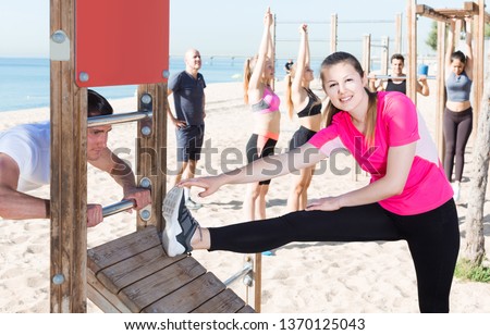 Smiling american people doing workout on beach in sunny morning