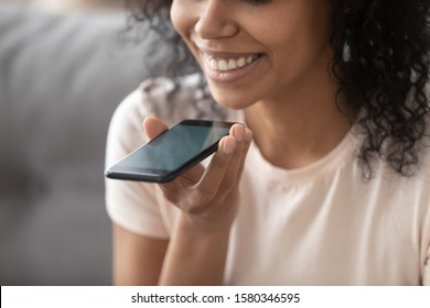 Smiling american woman speaking through microphone using loudspeaker speakerphone on smartphone close up focus on hand holding communication device, voice translator app, modern wireless tech concept - Powered by Shutterstock