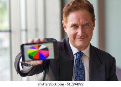 Smiling analyst demonstrating graph on phone - Powered by Shutterstock - Get 15% off with code: PIKWIZARD15