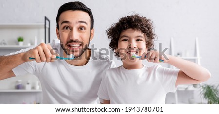Smiling arabian man and son brushing teeth, banner