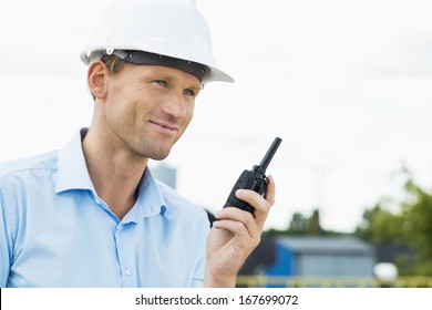 Smiling Architect Holding Two Way Radio At Construction Site