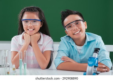 Smiling Asian Boy And Girl In Goggles Sitting In The Science Class