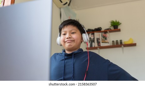 Smiling Asian Boy Holding Hands Behind Head Sitting Behind Use Computer Laptop. Happy Student Feeling Relaxing, After Learning Online Education Successful At Home