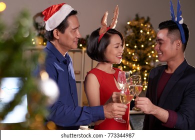 Smiling Asian business people drinking wine at Christmas celebration in office