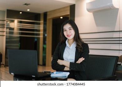 A Smiling Asian Business Woman Crossed Her Arms With Laptop In Office