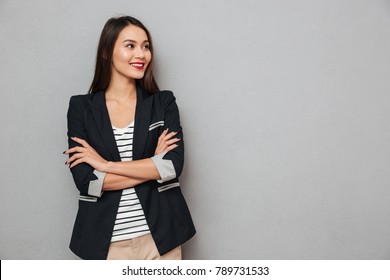 Smiling Asian Business Woman With Crossed Arms Looking Away Over Gray Background