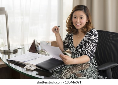 Smiling Asian Business Woman Holding Paper And Pen Wearing Black And White Dress 