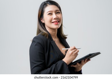Smiling asian business woman pointing up and looking at the camera over gray background