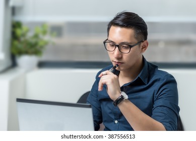 Smiling Asian Businessman Working In Front Of A Computer In The Office