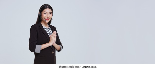 Smiling Asian Businesswoman Customer Support Phone Operator With Thai Culture Sawasdee,Welcome Expression Sawasdee Isolated Over Gray Background. Call Center And Customer Service Concept.