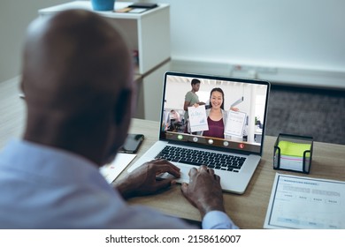Smiling asian businesswoman showing graphs and reports to african american male colleague on laptop. unaltered, office, online, technology, video conference, discussion, internet, business, teamwork. - Shutterstock ID 2158616007