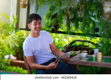 Smiling Asian Casual Man Reading Magazine 