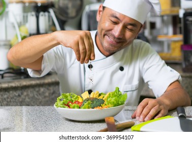 Smiling Asian Chef Add Spices In Salad. Focus On Hand And Spice.