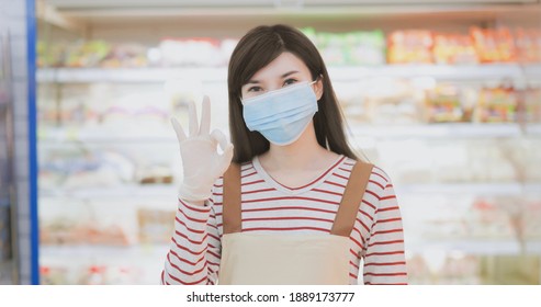 Smiling Asian Clerk Is Wearing Face Mask With Gloves At Grocery Store During Virus Epidemic Outbreak Then Shows Ok Gesture - Look To You