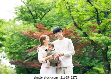 Smiling Asian couple and baby in green forest. Family concept. - Powered by Shutterstock