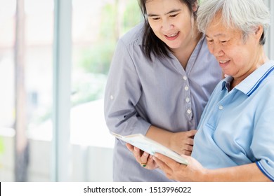 Smiling Asian Daughter Visit The Senior Mother And Watching At Photo Album,Alzheimer’s Disease In Elderly Patient Is Trying To Recall And Holding Old Photographs At Nursing Home,family Relationship