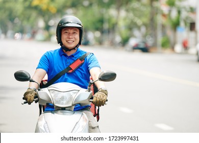 Smiling Asian Delivery Man Riding Scooter In The City And Delivering Products