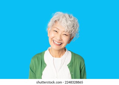 Smiling Asian elderly woman. Blue background. - Powered by Shutterstock