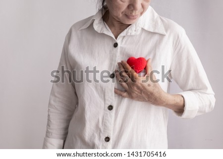 smiling asian elderly woman holding red heart shape, concept of prevention heart disease concept.