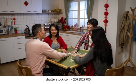 Smiling Asian Family Of Four Having Fun With Mahjong Game And Chatting Lively In The Evening At Home During Chinese Lunar New Year Holiday. Chinese Text At Background Translation: Luck