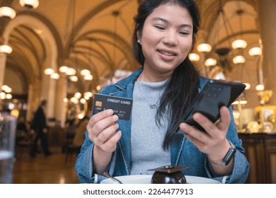 smiling asian female hand hold credit card sit relax casual at restaurant ,asian female hand hold credit card cashless lifestyle ideas concept,Asia woman show plastic credit card in restaurant