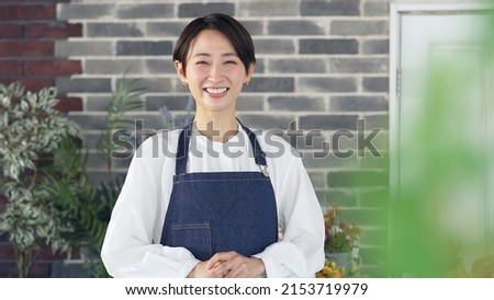 Smiling Asian female shop clerk. Restaurant. Flower shop.