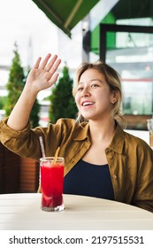 Smiling Asian Girl Waving To Someone In Cafe, Selective Focus