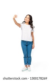 Smiling Asian Girl In White T-shirt And Blue Jeans Taking Selfie Isolated On White