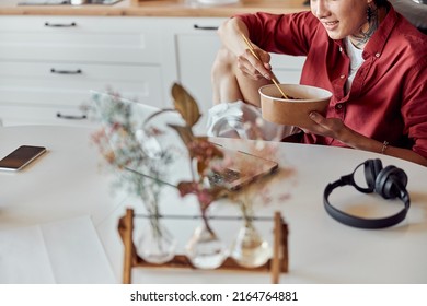 Smiling Asian Guy Eating Hot Instant Noodle And Work With Laptop