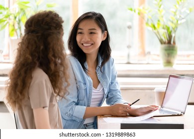 Smiling asian hr insurer advisor meeting applicant at job interview consulting client about contract offer giving advice, happy diverse girls colleagues interns students discussing paperwork together - Shutterstock ID 1319889863