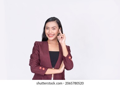 A smiling asian lady points her index finger to her temple. Concept of being smart or having a bright idea. Isolated on a white background. - Shutterstock ID 2065780520