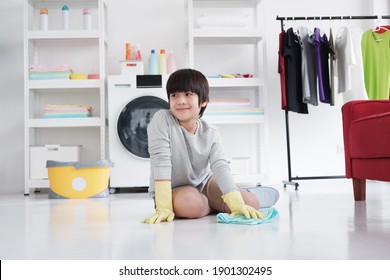 Smiling Asian Little Boy Child Is Enjoying For House Cleaning In Laundry Room. He Is Mopping The Floor. Homeschool And Family Time On Holiday Concept.